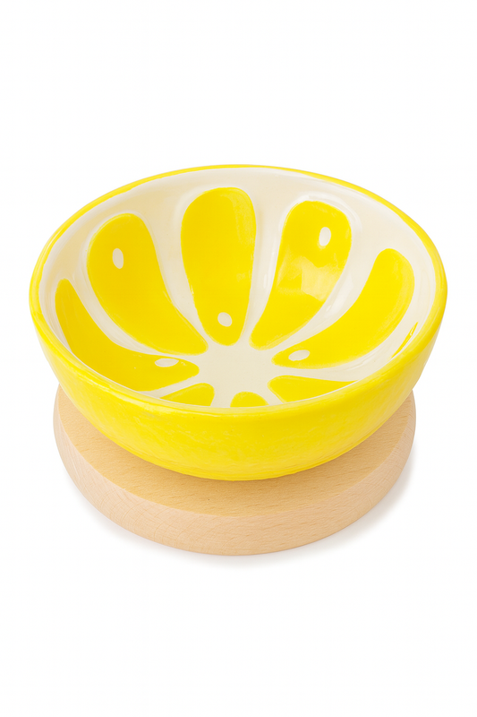 Alt tekst: „Żółta ceramiczna miseczka z białym wnętrzem ozdobionym wzorem przypominającym plaster cytryny, ustawiona na jasnej, drewnianej podstawce – stylowa dekoracja i praktyczny element zastawy stołowej.