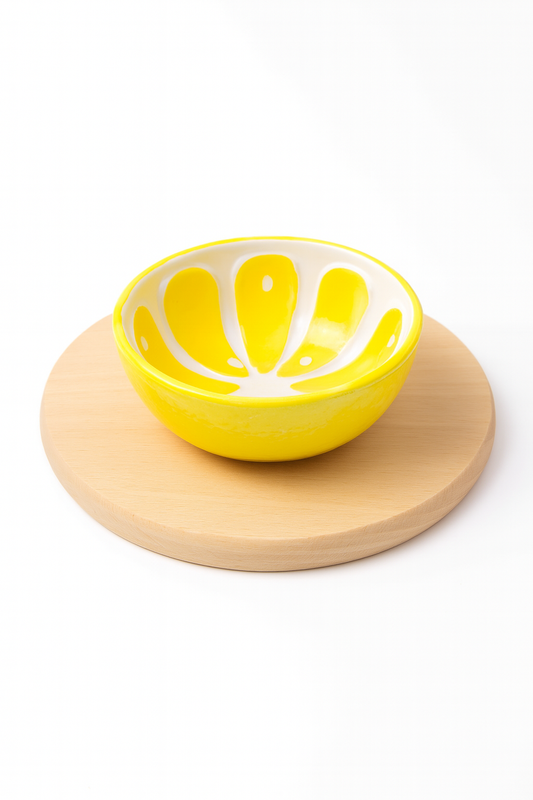 Żółta ceramiczna miseczka w kształcie plasterka cytryny ustawiona na okrągłej drewnianej desce z jasnego drewna – produkt dekoracyjny i kuchenny marki Chłopcy z Rancza.