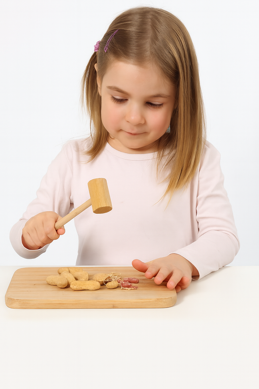 Dziewczynka rozbija orzechy ziemne drewnianym tłuczkiem na desce kuchennej – naturalna scena domowa, produkt Chłopcy z Rancza, drewniany tłuczek 16 cm