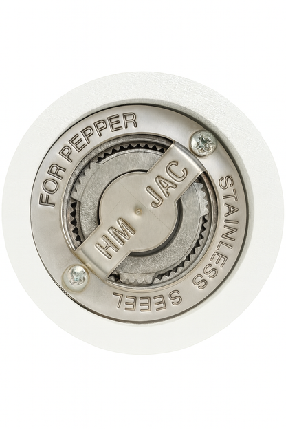 Zbliżenie na stalowy mechanizm młynka do pieprzu z grawerem ‘HM JAC’ i napisami ‘FOR PEPPER’ oraz ‘STAINLESS STEEL’, osadzony w pomalowanym na biało, drewnianym korpusie.