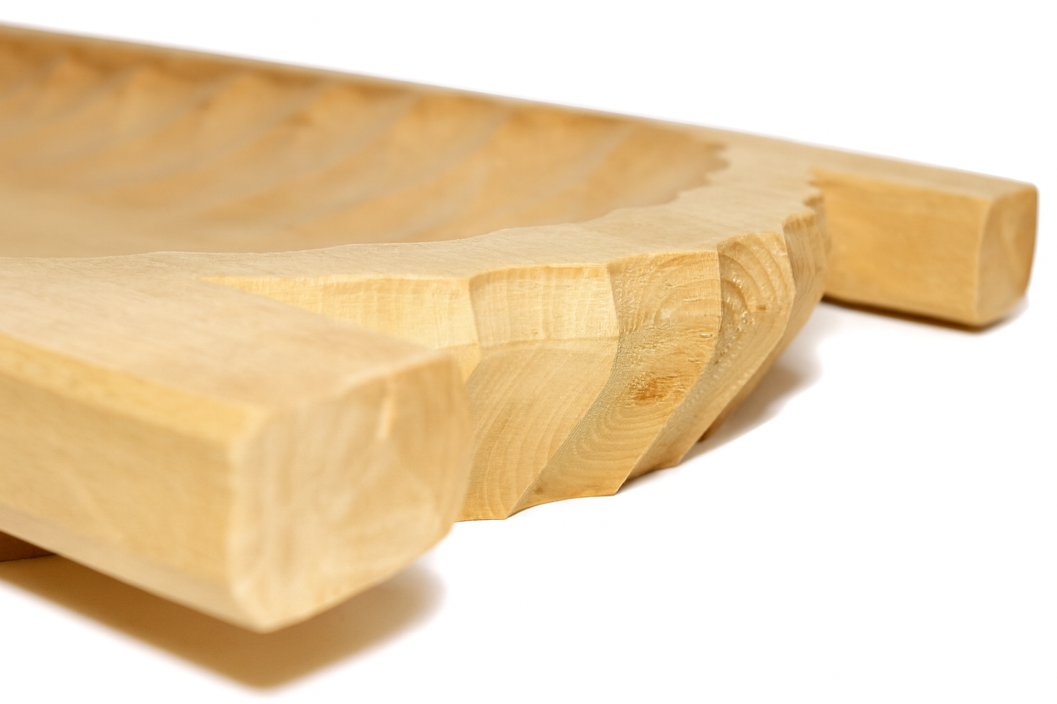 Zbliżenie na ręcznie rzeźbione koryto drewniane w kolorze jasnej lipy. Widoczna faktura i słoje drewna oraz precyzyjne wyżłobienia na krawędzi