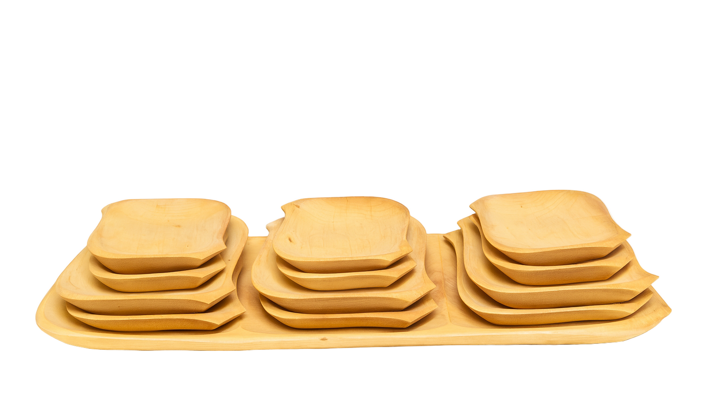 Zestaw drewnianych talerzy w trzech stosach ułożonych na prostokątnej tacy z jasnego drewna bukowego. Każdy stos zawiera talerze o różnych rozmiarach, z zaokrąglonymi krawędziami i naturalnym usłojeniem. Zdjęcie na białym tle, w orientacji poziomej, styl e-commerce – czyste, jasne światło podkreślające fakturę drewna.