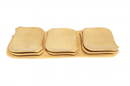 Zestaw czterech kompletów prostokątnych talerzy z naturalnego drewna, ułożonych w rzędzie na dużej drewnianej tacy. Jasne, gładkie drewno z widocznym usłojeniem.